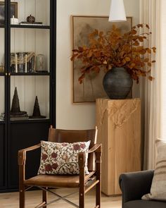 a living room filled with furniture and a vase on top of a book shelf next to a window