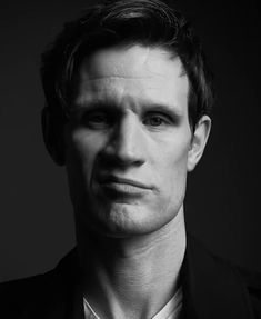 a black and white photo of a man in a suit looking at the camera with a serious look on his face