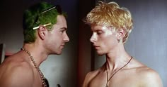 two men with blonde hair and green wigs looking at each other's faces