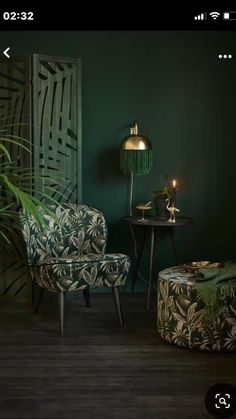 a living room with two chairs and a table in front of a green painted wall