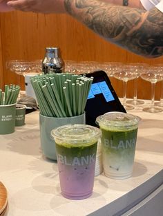 two cups filled with green drinks sitting on top of a counter