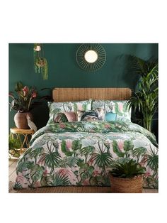 a bedroom with green walls and palm leaves on the comforter, along with potted plants