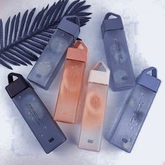 four different types of water bottles next to a palm leaf and another type of bottle