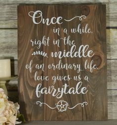 a wooden sign that says, once in a while right in the middle of an ordinary life love gives us fairy tale