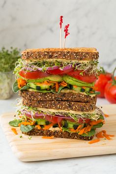 the sandwich is stacked on top of each other with lettuce, tomato and cucumber