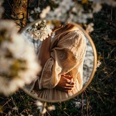 a woman standing in front of a mirror next to flowers