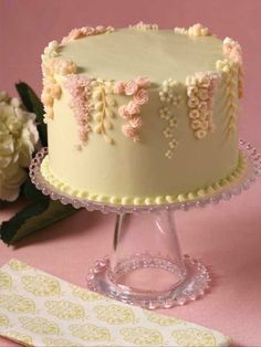 a white cake sitting on top of a table next to a pink napkin and flowers