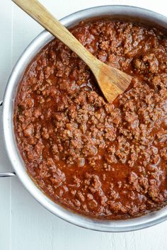 a large pot filled with chili sauce and a wooden spoon in the bottom left corner