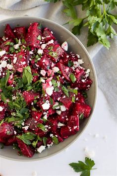 a bowl filled with beets, feta cheese and cilantro on top of a table