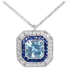 Presenting an exquisite platinum pendant showcasing a bezel-set, natural Asscher-cut aquamarine weighing 1.05 carats. Encircling the center stone are halos of meticulously calibrated French-cut sapphires and round brilliant-cut diamonds, accentuated with delicate milgrain detailing. The pendant's geometric design pays homage to the timeless elegance of the Art Deco era, evoking an era of sophistication and glamour. This remarkable piece seamlessly blends modern craftsmanship with vintage-inspire Stone Pendent Designs, Platinum Pendant, Halo Art, Aquamarine Pendant, Art Deco Pendant, French Cut, Asscher Cut, Estilo Art Deco, Art Deco Era