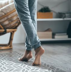 a woman standing on top of a wooden floor next to a chair and foot rest