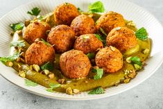 a white plate topped with meatballs covered in green sauce