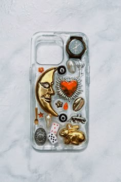 a phone case with various items on it sitting on a marble surface next to a clock