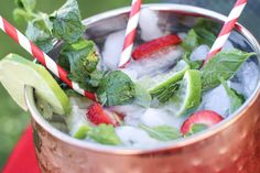 two strawberries and limes in a copper cup with ice