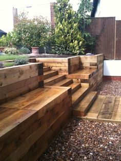 wooden steps leading up to the side of a house with gravel on the ground and trees in the background