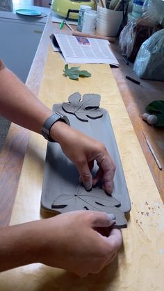 a person cutting out paper leaves on top of a wooden table