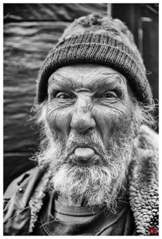 a black and white photo of an old man with a beard wearing a beanie