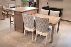 a dining room table with chairs around it in front of a kitchen island and cabinets