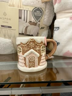 a coffee mug with a gingerbread house on it sits in front of some teddy bears