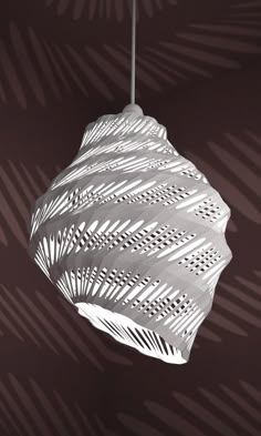 a white light hanging from a ceiling in front of a palm leaf pattern on the wall