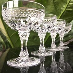 four crystal goblets sitting on top of a black table