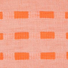 an orange and white fabric with small squares on the top of it, as well as some smaller dots