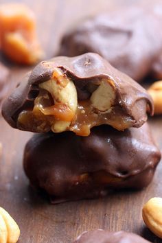 chocolate covered cookies with nuts on top and in the middle, sitting on a wooden surface