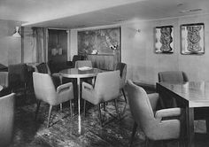 a black and white photo of a dining room with tables, chairs and pictures on the wall