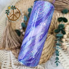 a purple and blue tumbler sitting on top of a table next to some plants