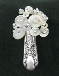 a silver spoon with white flowers and pearls on it