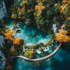 an aerial view of a bridge in the middle of a river surrounded by trees and rocks