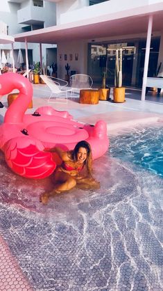 a woman sitting on top of an inflatable flamingo next to a swimming pool