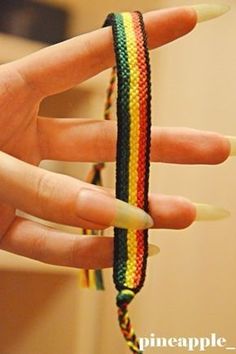 a woman's hand holding onto a multicolored bracelet with white tip nails