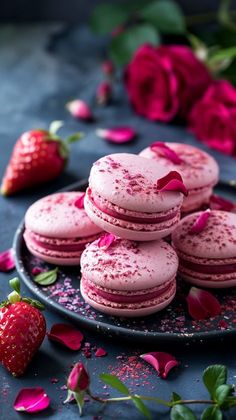 pink macaroons and strawberries on a black plate