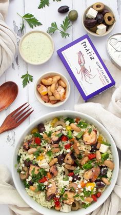 a white bowl filled with salad next to olives, cheese and other food items