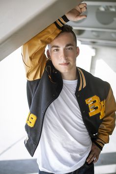 a young man wearing a jacket and white t - shirt is posing for the camera