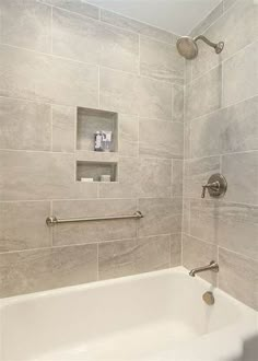 a white bath tub sitting inside of a bathroom next to a shower head and hand rail