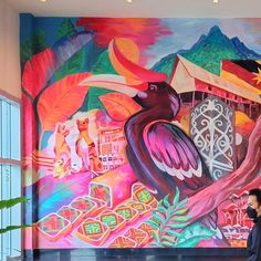 a man standing in front of a colorful mural