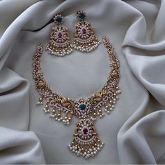 Elevate your bridal ensemble with this exquisite Peacock Matte Gold Finish Haram Necklace and Jhumka Earrings set. This stunning jewelry set is a perfect blend of traditional South Indian craftsmanship and contemporary elegance, designed to make you shine on your special day. ### Features: **Peacock Matte Gold Finish The necklace and earrings boast a luxurious matte gold finish, giving them an antique and regal look, perfect for any Bollywood-inspired wedding. **Intricate Design The set features Luxury Kundan Earrings With Peacock Design, Luxury Bridal Necklace With Peacock Design, Luxury Wedding Chandbalis With Peacock Design, Luxury Temple Necklace With Peacock Design For Wedding, Luxury Peacock Design Necklace In Temple Jewelry Style, Temple Jewelry Sets With Peacock Design For Weddings, Wedding Kundan Chandbalis With Peacock Design, Temple Jewelry Peacock Design Jhumkas For Wedding, Wedding Jhumkas With Peacock Design In Temple Jewelry Style