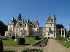 a large building with many windows and towers on it's sides, surrounded by greenery