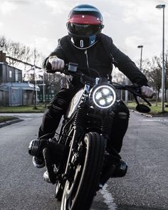 a man riding on the back of a motorcycle down a street