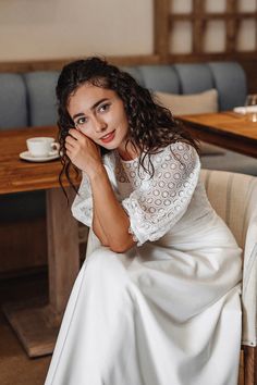 a woman sitting at a table in a white dress