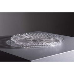 a clear glass plate sitting on top of a metal tablecloth covered counter with shadows