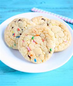 three cookies with sprinkles on a white plate