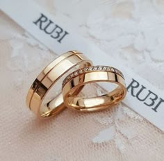 two gold wedding rings sitting on top of each other