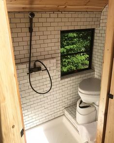 a bathroom with a toilet and shower head mounted to the wall next to a window