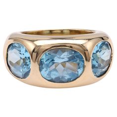 a gold ring with blue topaz and two oval stones on the front, set in 18k yellow gold