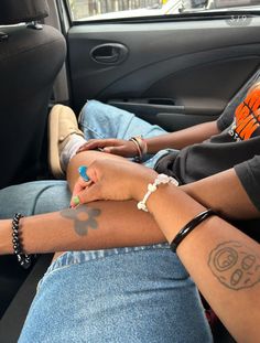 two people sitting in the back seat of a car with tattoos on their arms and legs