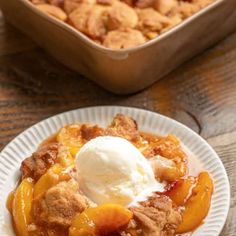 a white plate topped with fruit cobbler next to a baking pan filled with ice cream