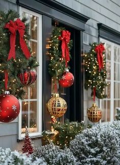 christmas decorations are hanging on the windows in front of a building with red and gold baubles